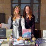 Las escritoras Almu Bree y Pat MM posan en el stand de Zsa Zsa Zsú Ediciones en el Mercado Medieval de Atienza